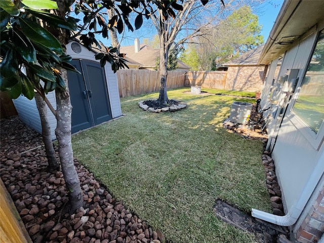 view of yard featuring a storage unit, an outdoor structure, and a fenced backyard