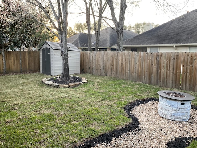 view of yard featuring an outbuilding, an outdoor fire pit, a storage shed, and a fenced backyard