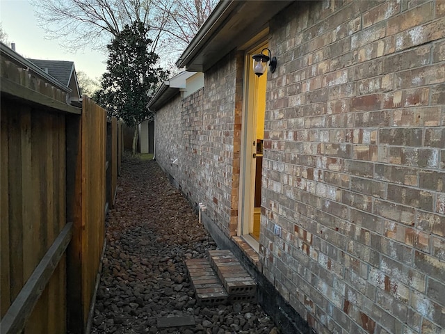 view of side of property featuring fence and brick siding