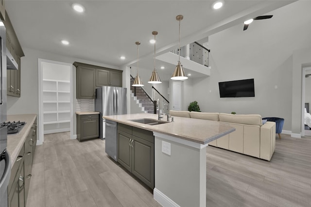 kitchen with tasteful backsplash, open floor plan, stainless steel appliances, gray cabinets, and a sink