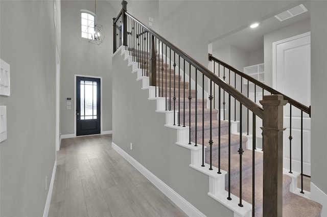 entrance foyer with baseboards, a high ceiling, visible vents, and wood finished floors