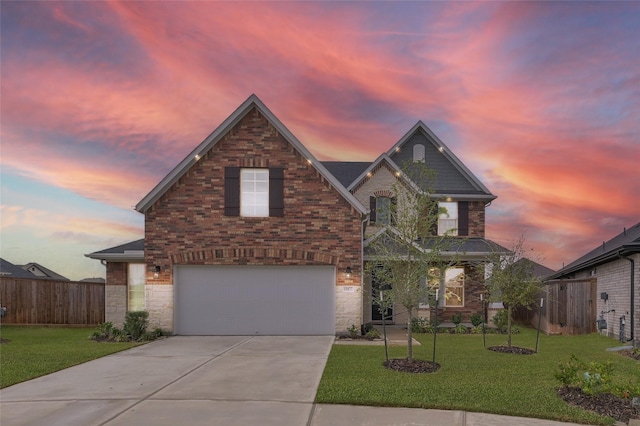 traditional-style home with driveway, a garage, fence, a yard, and brick siding