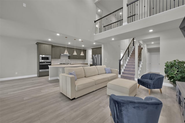 living room featuring light wood-style flooring, stairway, baseboards, and recessed lighting