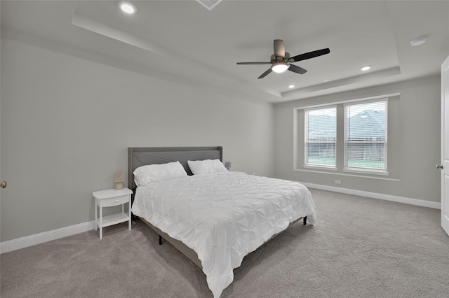 bedroom with a tray ceiling, carpet flooring, and baseboards