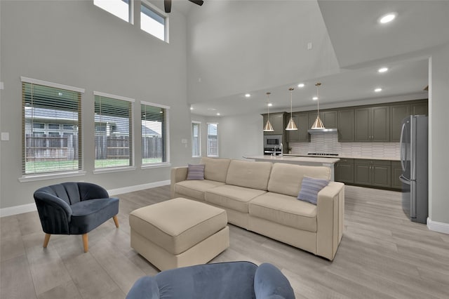 living area with recessed lighting, light wood-style flooring, and baseboards