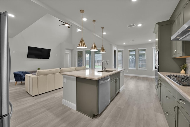 kitchen with visible vents, gray cabinetry, appliances with stainless steel finishes, a sink, and wall chimney range hood