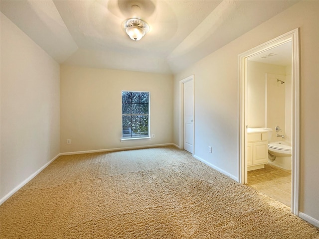 spare room with baseboards, vaulted ceiling, and light colored carpet