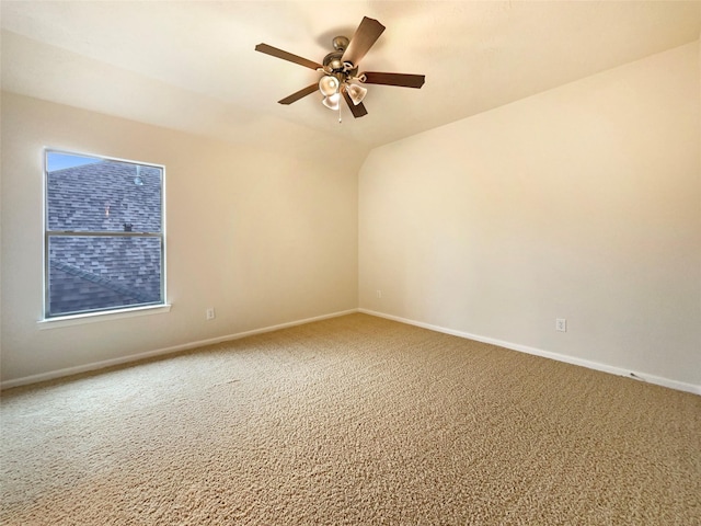 carpeted empty room featuring ceiling fan, baseboards, and vaulted ceiling