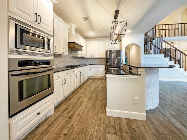 kitchen featuring dark countertops, backsplash, custom exhaust hood, and wood finished floors