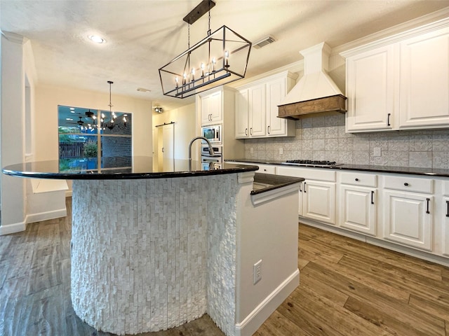 kitchen with white cabinets, visible vents, custom exhaust hood, and wood finished floors