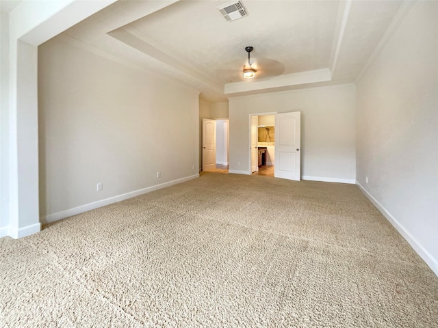 unfurnished bedroom featuring visible vents, baseboards, ornamental molding, a tray ceiling, and a walk in closet