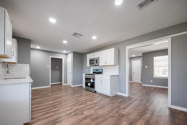 kitchen featuring visible vents, dark wood-type flooring, stainless steel appliances, light countertops, and a sink