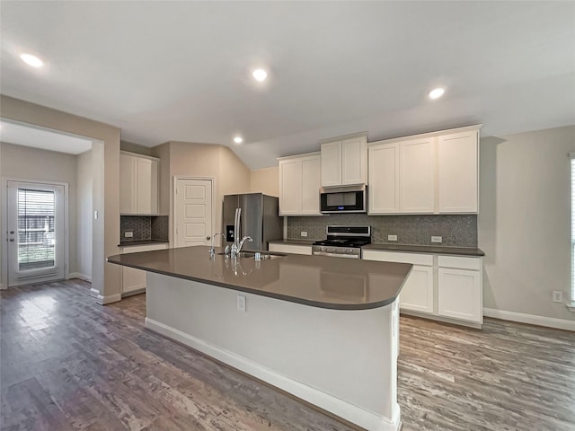 kitchen with wood finished floors, appliances with stainless steel finishes, an island with sink, and a sink