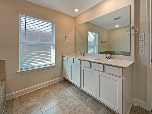 bathroom with double vanity, baseboards, visible vents, and a sink