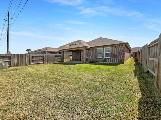 rear view of house featuring a fenced backyard, brick siding, a shingled roof, a lawn, and a patio area