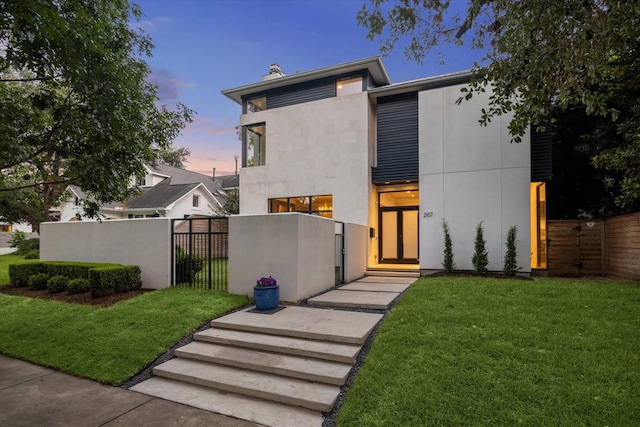 contemporary home featuring a fenced front yard, a chimney, stucco siding, a gate, and a front lawn