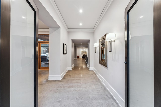 corridor with concrete flooring, recessed lighting, ornamental molding, and baseboards