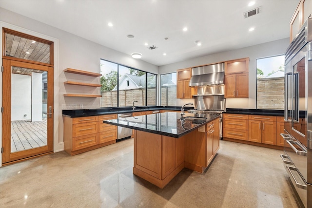 kitchen with visible vents, dishwasher, wall chimney range hood, and a sink