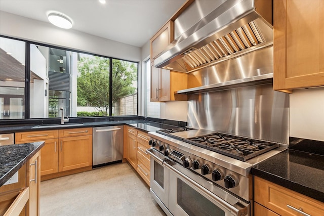 kitchen with stainless steel appliances, premium range hood, a sink, brown cabinets, and dark stone counters