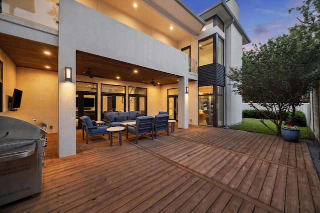 deck at dusk with a ceiling fan, an outdoor living space, and area for grilling