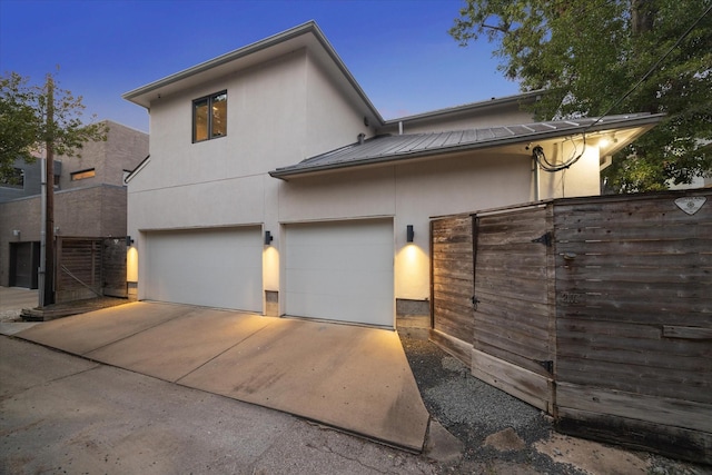 view of front of home featuring stucco siding, a standing seam roof, metal roof, a garage, and driveway