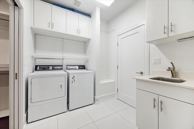 washroom with light tile patterned floors, a sink, visible vents, washer and dryer, and cabinet space