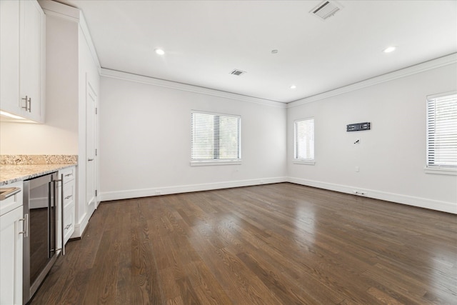 interior space with wine cooler, dark wood-style flooring, crown molding, visible vents, and baseboards