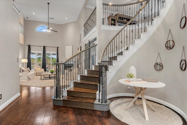 stairway with crown molding, ceiling fan, baseboards, a towering ceiling, and hardwood / wood-style flooring