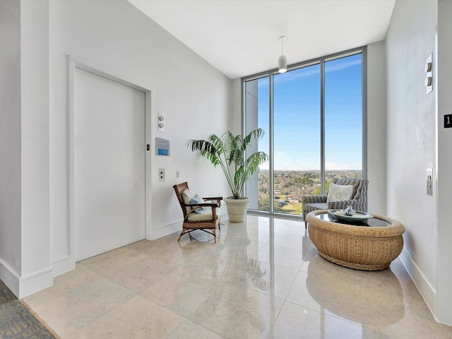 sitting room with baseboards, elevator, and floor to ceiling windows