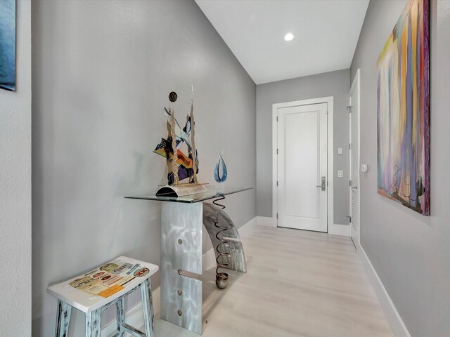 corridor with baseboards, wood finished floors, and recessed lighting