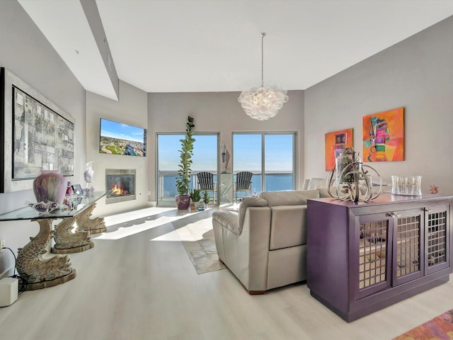 living room with a glass covered fireplace, a notable chandelier, and wood finished floors