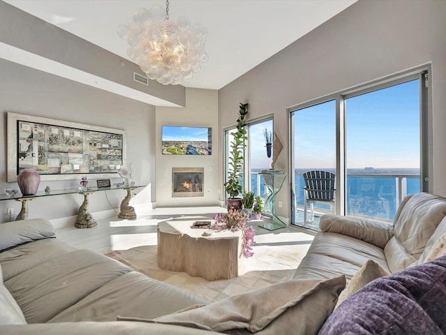 living room featuring baseboards, visible vents, a notable chandelier, and a glass covered fireplace