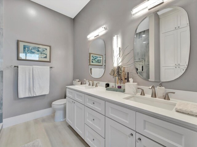 bathroom with double vanity, a sink, toilet, and wood finished floors