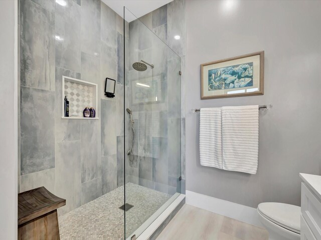 full bathroom featuring toilet, tiled shower, and vanity