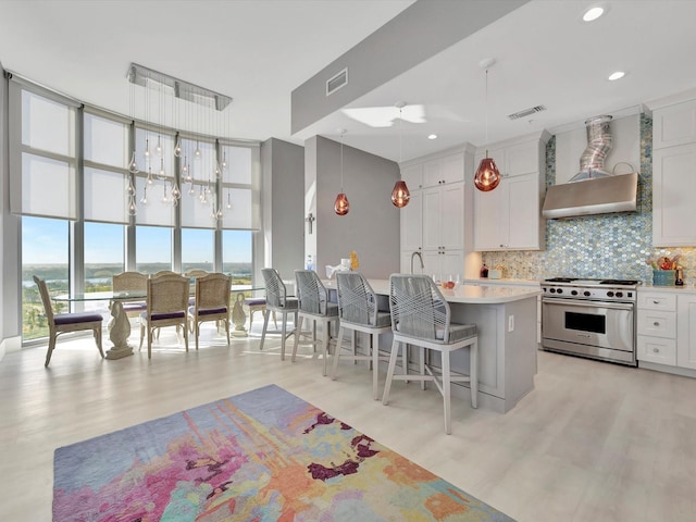 kitchen with tasteful backsplash, visible vents, designer stove, light countertops, and light wood-type flooring