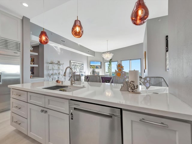 kitchen featuring appliances with stainless steel finishes, light countertops, a sink, and decorative light fixtures