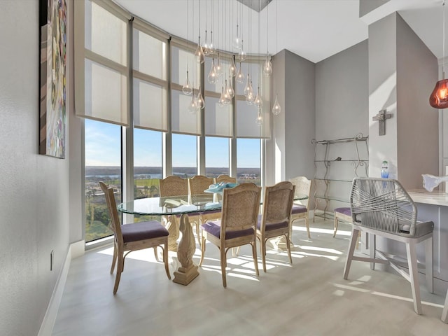 dining room featuring a towering ceiling, baseboards, a chandelier, and a wealth of natural light