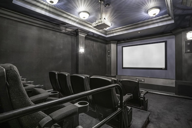 cinema room with a tray ceiling, crown molding, and carpet flooring