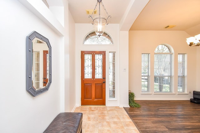 entrance foyer with baseboards, visible vents, and a notable chandelier