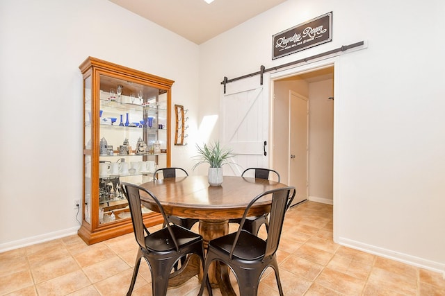 dining area with light tile patterned floors, a barn door, and baseboards