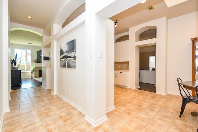 corridor with light tile patterned floors, visible vents, and baseboards