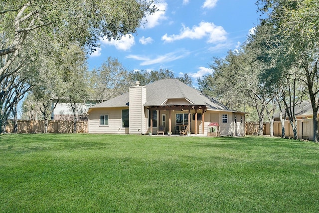 back of house featuring a fenced backyard, a chimney, a patio, and a yard