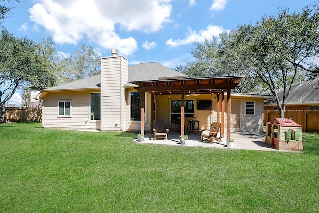 rear view of property with a patio, fence, a yard, roof with shingles, and a chimney