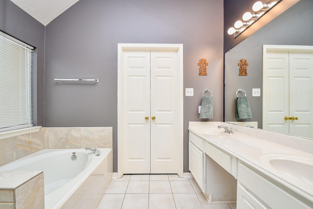 bathroom with a closet, a sink, a bath, and tile patterned floors