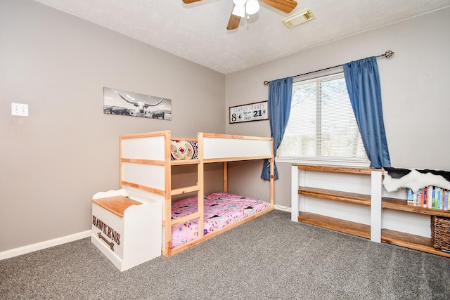 carpeted bedroom featuring baseboards, a textured ceiling, visible vents, and a ceiling fan