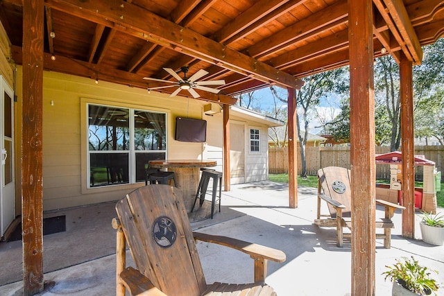 view of patio / terrace with outdoor dry bar, fence, and a ceiling fan