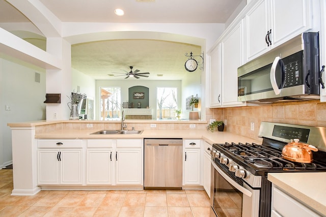 kitchen with stainless steel appliances, white cabinets, a sink, and tasteful backsplash