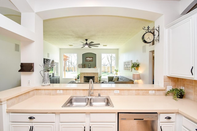 kitchen with ceiling fan, open floor plan, a peninsula, stainless steel dishwasher, and a sink