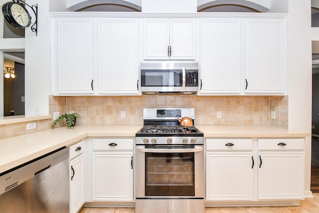 kitchen with light countertops, appliances with stainless steel finishes, white cabinets, and tasteful backsplash