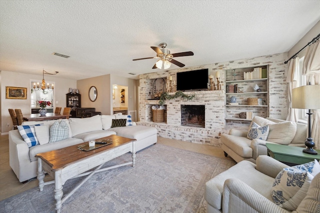 living area with a textured ceiling, ceiling fan with notable chandelier, visible vents, a brick fireplace, and tile patterned floors